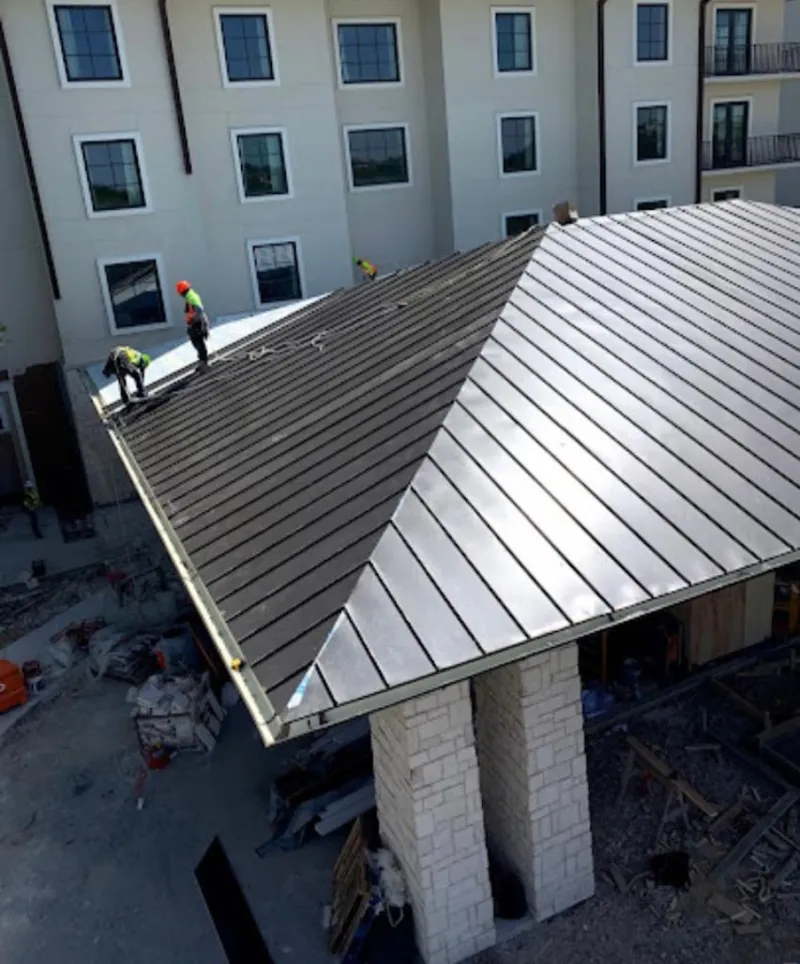 Crew installing standing seam metal roof panels on a commercial project in Scituate